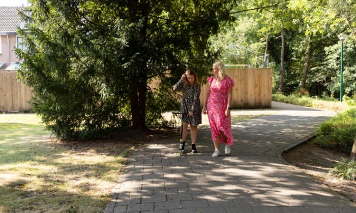 Hulpverlener en meisje lopen op straat Kind en hulpverlener lopen buiten en zijn in gesprek