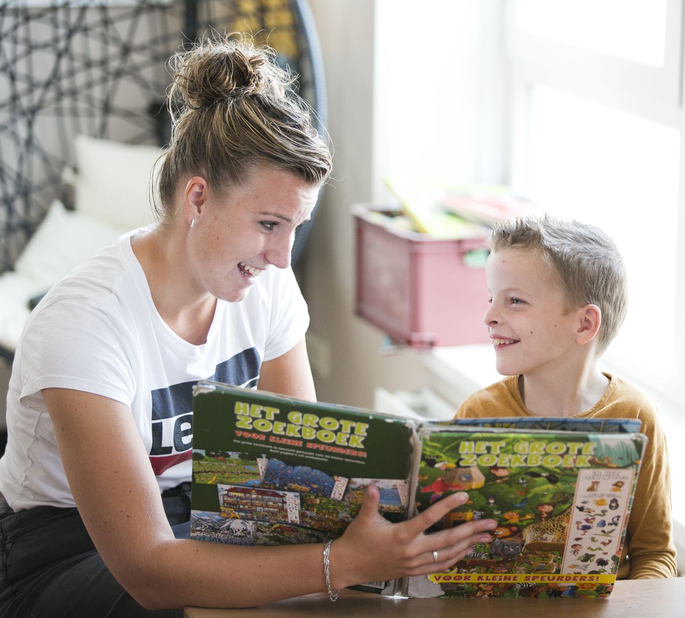 Hulpverlener leest voor aan kind aan tafel op school Hulpverlener in het onderwijs leest boek voor aan jong kind aan tafel