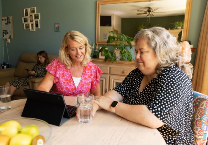 Hulpverlener moeder opvoeder aan tafel met tablet in gesprek vacature hulpverlening Hulpverlener moeder opvoeder aan tafel met tablet in gesprek vacature hulpverlening