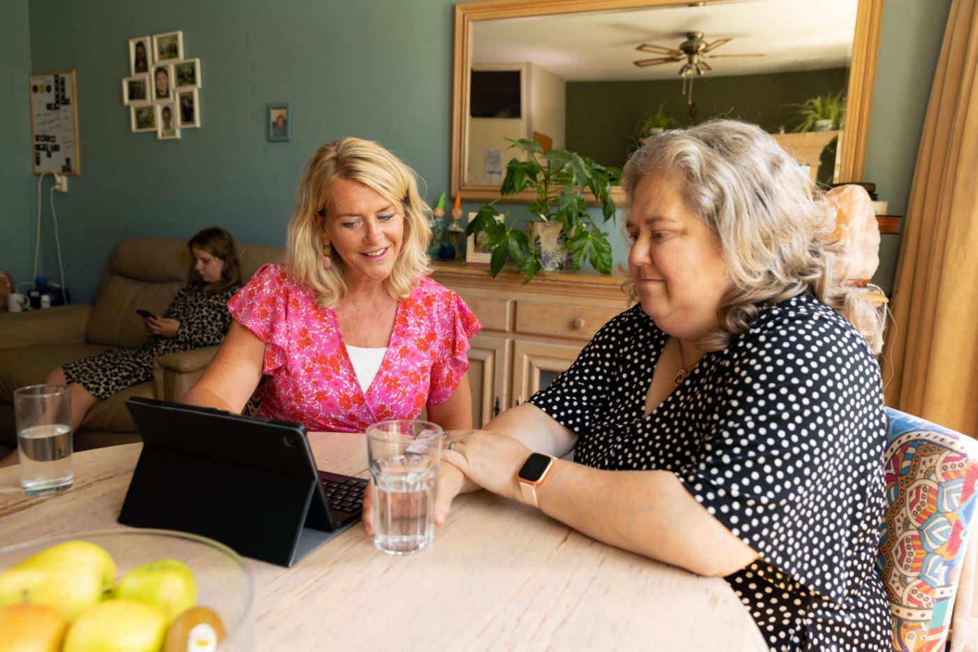 Hulpverlener moeder opvoeder aan tafel met tablet in gesprek Hulpverlener is in gesprek over opvoeding met moeder met een tablet aan tafel