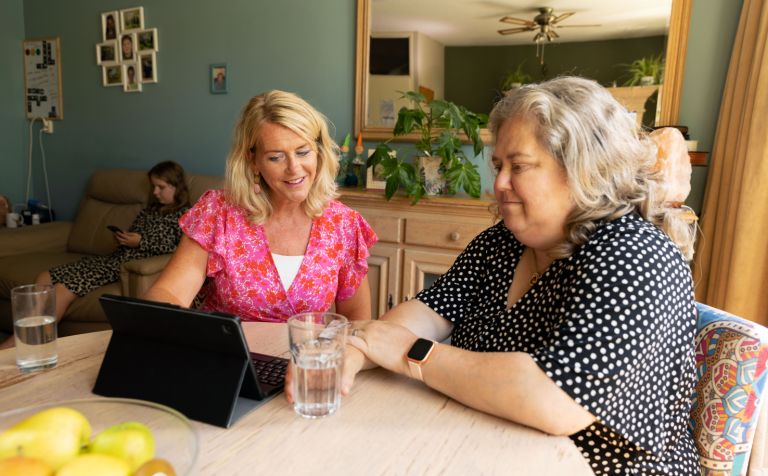 Hulpverlener moeder opvoeder aan tafel met tablet in gesprek Hulpverlener is in gesprek over opvoeding met moeder met een tablet aan tafel
