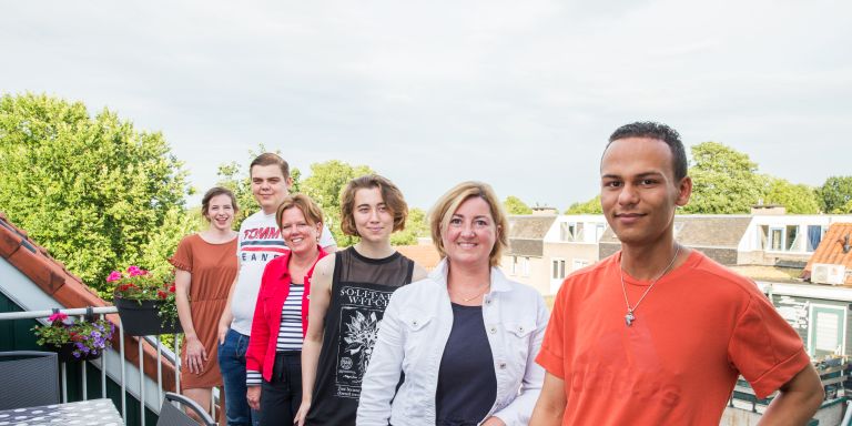 Hulpverleners cliënten netwerk groepsfoto Groepsfoto van vrouwelijke hulpverleners en jongeren op een balkon naast een tafel in een woonwijk