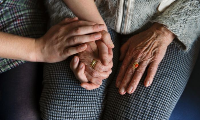 Jonge en oude handen op elkaar Jonge handen houden oude handen met ring vast op schoot