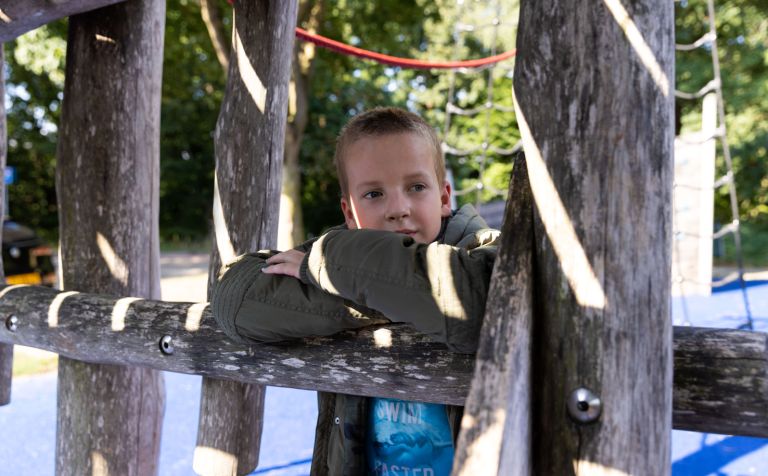 Jongen cliënt buitenspeeltuin Jong kind speelt in een buitenspeeltuin