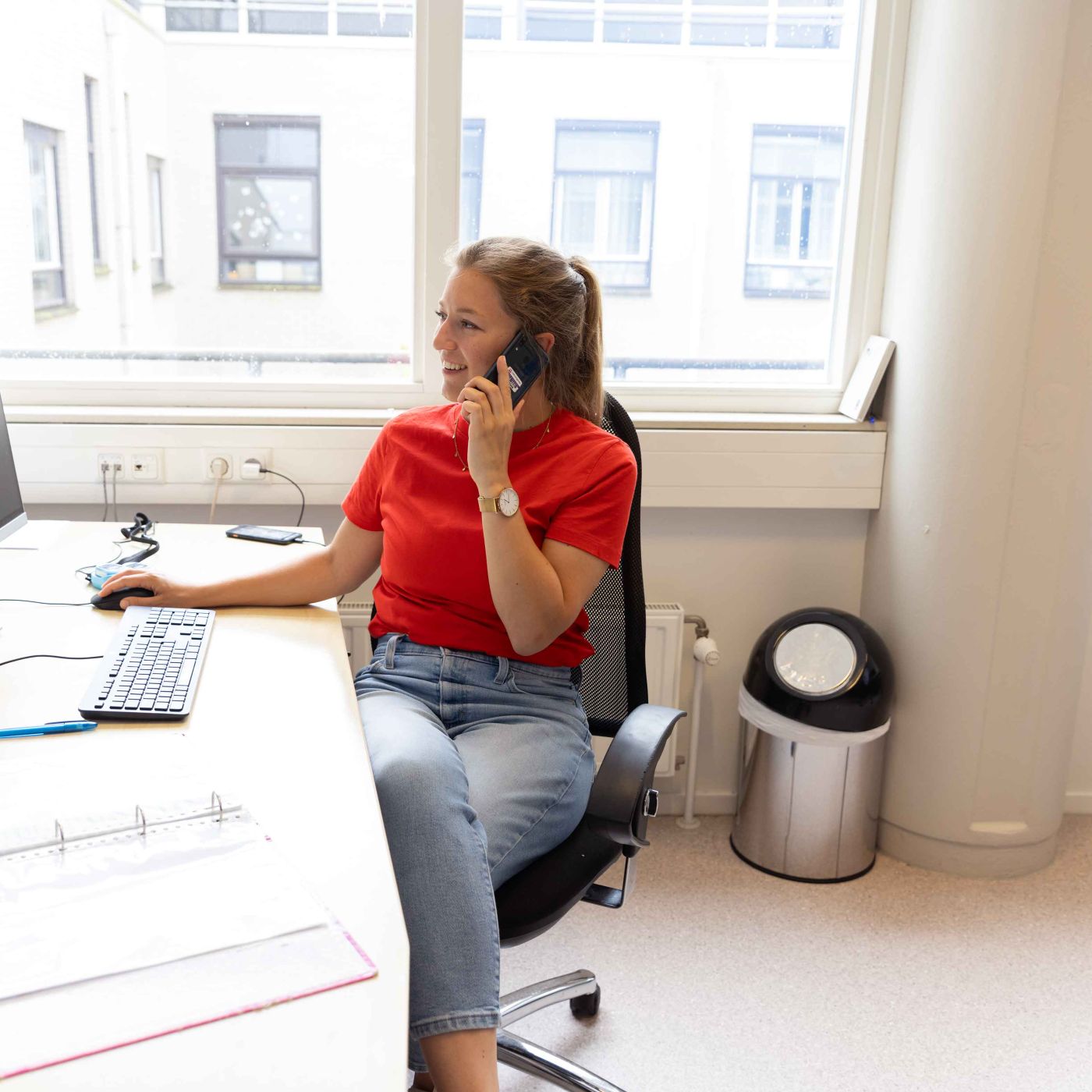 Medewerker Christine Slings bureau computer vacature administratie service contact receptie telefoniste ondersteuning zonderuniform Medewerker zit achter een bureau en kijkt op de computer