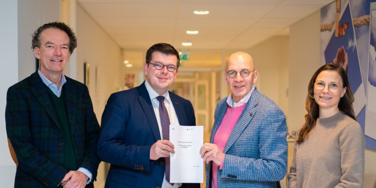 Pagina_Samenwerkingen_LelieCHEOndertekening Vier mensen van Lelie zorggroep en de Christelijke Hogeschool Ede poseren met een samenwerkingsovereenkomst.