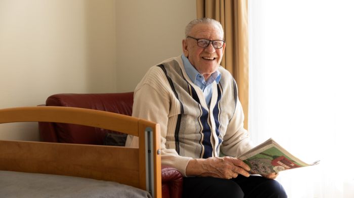 Portret bewoner client Riederborgh Ridderkerk Oude meneer kijkt de camera in en zit op een stoel met een krant in zijn hand