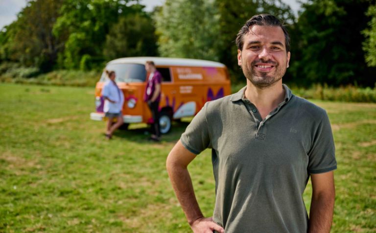 Portret liggend Stephan voor bus waardering achtergrond collega's Portret van man met hand in de zij voor de bus vol waardering van Lelie zorggroep