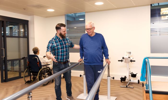 Revalidatie oefening lopen man met zorgverlener Cliënt en zorgverlener doen revalidatie oefeningen in afdeling schenkel in Rotterdam in het IJsselland ziekenhuis