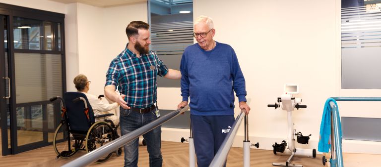 Revalidatie oefening lopen man met zorgverlener Cliënt en zorgverlener doen revalidatie oefeningen in afdeling schenkel in Rotterdam in het IJsselland ziekenhuis