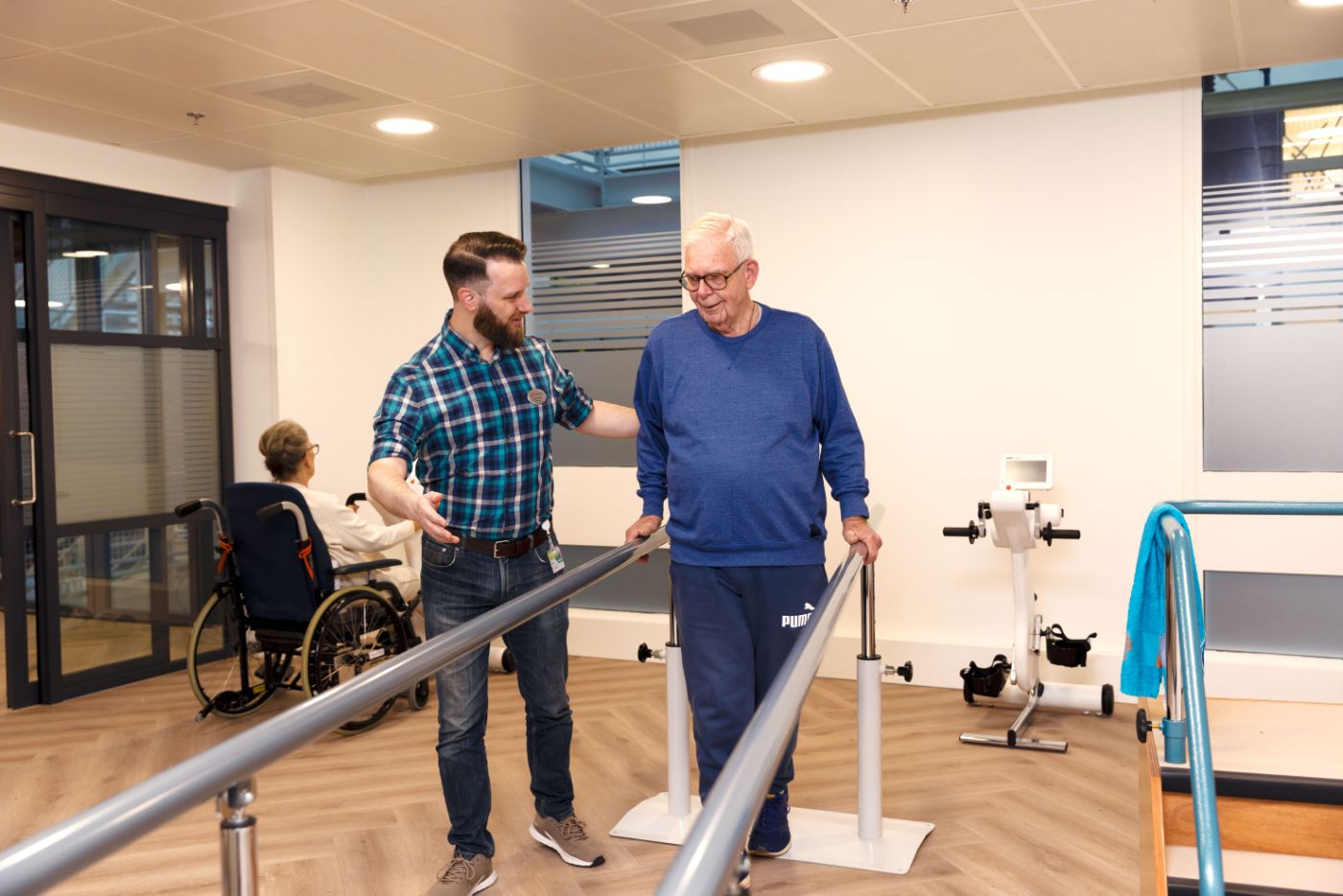 Revalidatie oefening lopen man met zorgverlener Meneer doet samen met behandelaar een revalidatie oefening