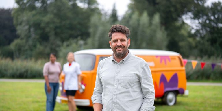 Man van christelijke zorgorganisatie Lelie Zorggroep in Rotterdam vacature ondersteuning hulpverlening zonderuniform bus vol waardering huishouden Man poseert glimlachend voor oranje vintage volkswagenbusje van Lelie zorggroep