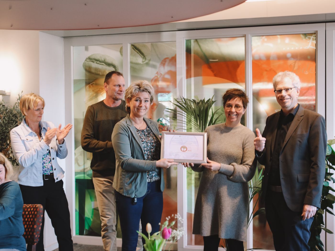 Uitreiking bronzen keurmerk Milieu Platform Zorgsector aan locatie Oranjehof Groepsfoto waarbij de locatiemanager van verpleeghuis Oranjehof het bronzen keurmerk krijgt van de directeur van Milieu Platform Zorgsector