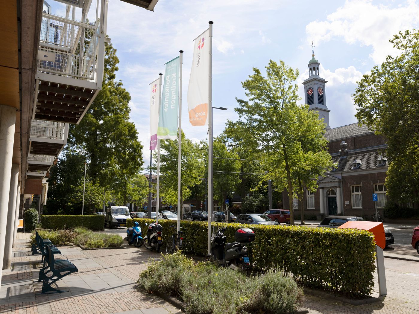 Verpleeghuis Pniel ingang met welkomstvlaggen Verpleeghuis Pniel in Rotterdam Kralingen met vlaggen aan de voorkant en uitzicht op een kerk en auto's aan de weg