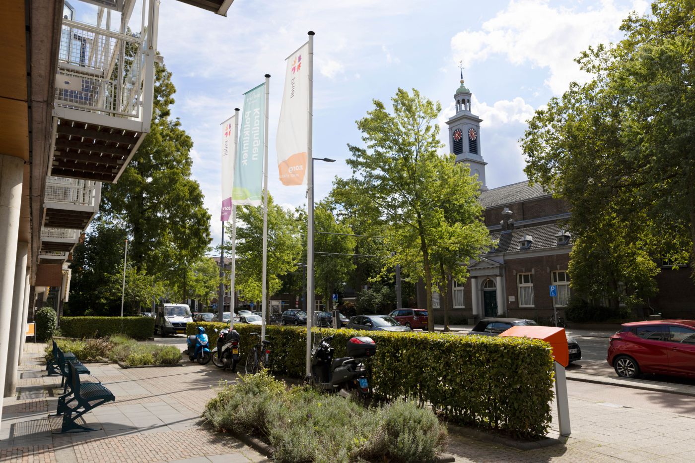 Verpleeghuis Pniel ingang met welkomstvlaggen Verpleeghuis Pniel in Rotterdam Kralingen met vlaggen aan de voorkant en uitzicht op een kerk en auto's aan de weg
