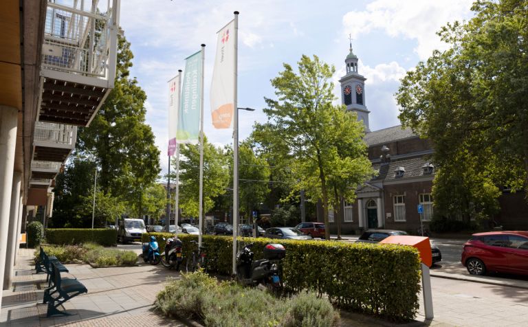 Verpleeghuis Pniel ingang met welkomstvlaggen Verpleeghuis Pniel in Rotterdam Kralingen met vlaggen aan de voorkant en uitzicht op een kerk en auto's aan de weg