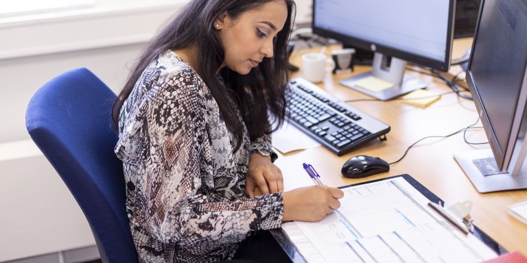 Zorgadviseur computer schrijven werken kantoor vacature service organisatie Vrouwelijke zorgadviseur van Lelie zorggroep zit achter een computer op kantoor en schrijft in documenten