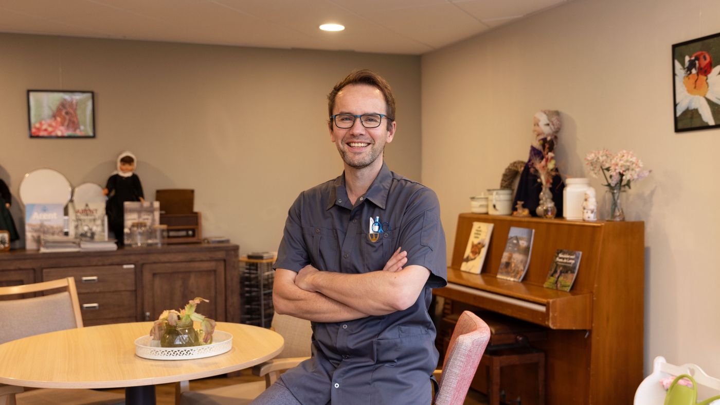 Verpleeghuiszorg Het Nieuwe Feithenhof Veluwe uniform vacature portret medewerker man Verpleeghuiszorg Het Nieuwe Feithenhof Veluwe verzorgende grijze zorgjasje vacature portret medewerker man